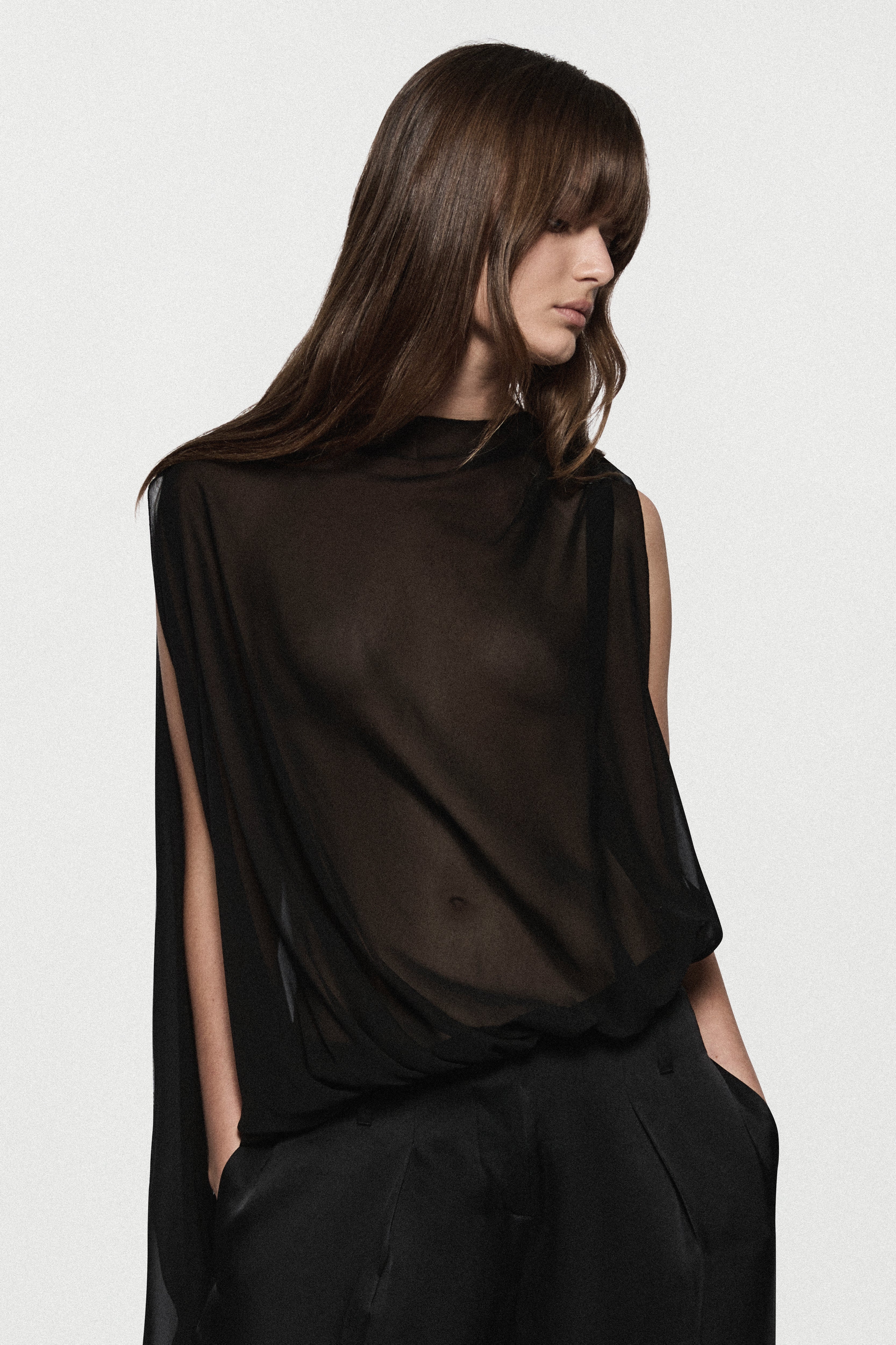 Black sheer sleeveless silk blouse with high neck and flowing drape detail
