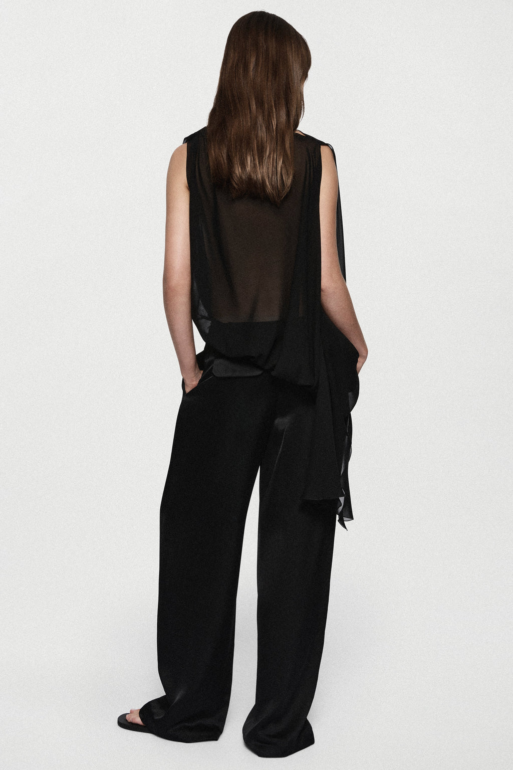 Back view of black sheer sleeveless silk blouse with high neck and waist ties