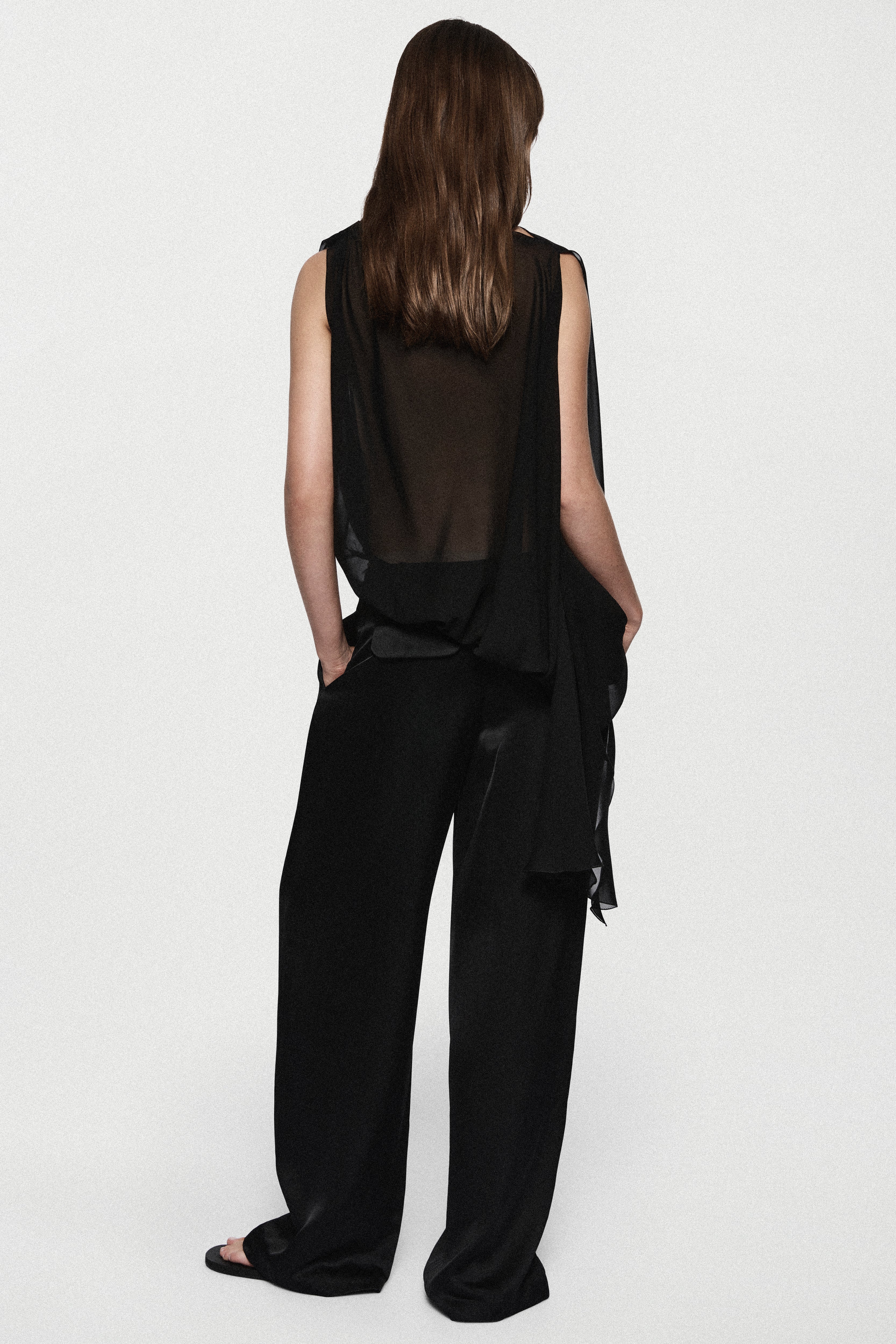 Back view of black sheer sleeveless silk blouse with high neck and waist ties