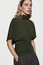 Hunter green cape jersey turtleneck top with short sleeves and draped waist gathers.