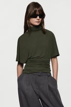 Hunter green cape jersey turtleneck top, short sleeves, ruched hem and folds.