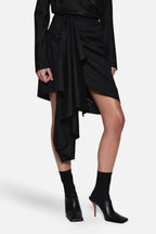 Black draped wool suiting skirt close-up of twisted waist and cascading hem layers