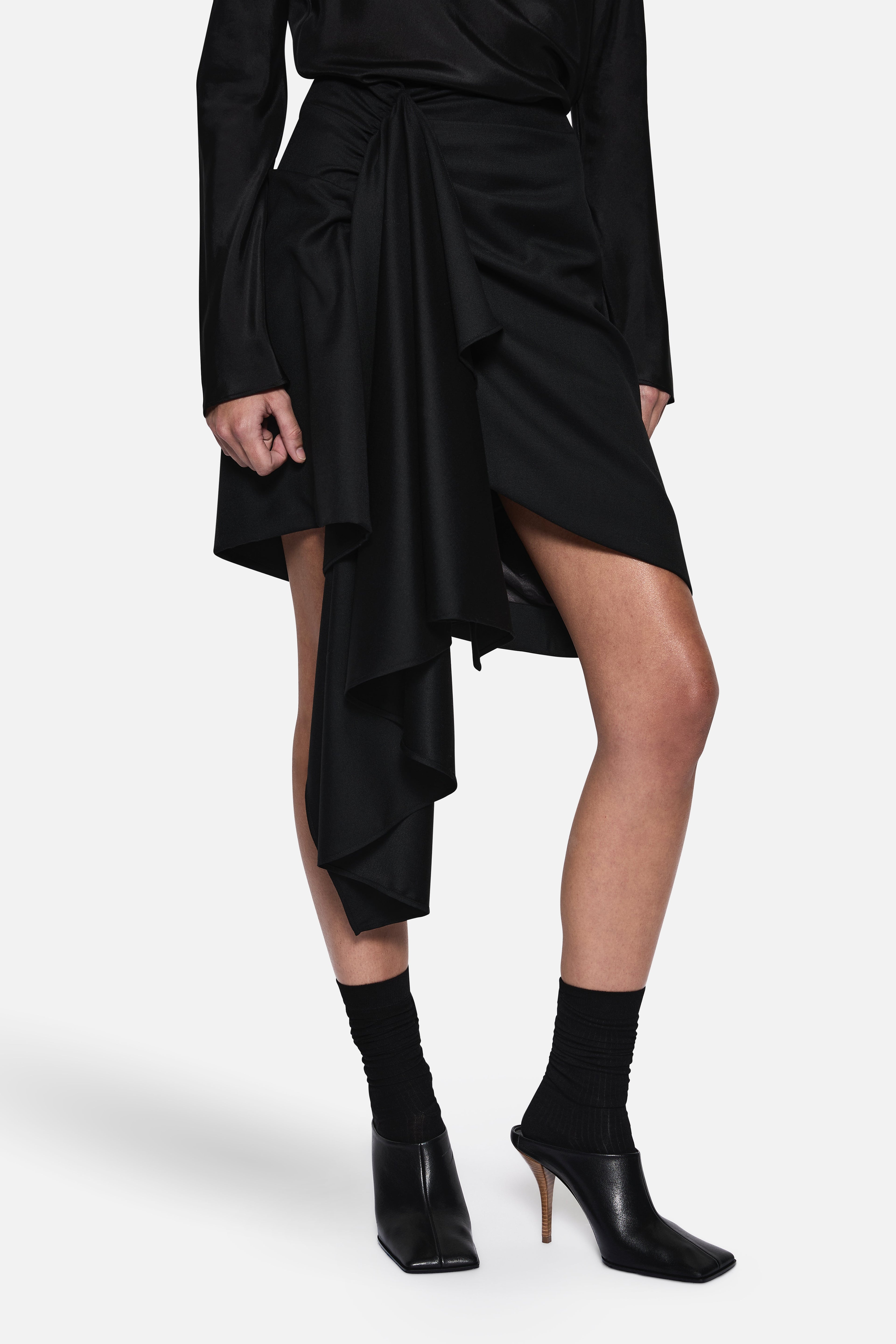 Black draped wool suiting skirt close-up of twisted waist and cascading hem layers