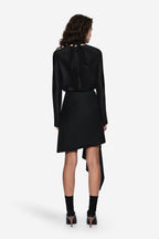Black draped wool suiting skirt, back view, with draped panels and asymmetrical hem