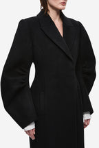 Black wool tailored long coat with notched lapels and deep V neckline detail.