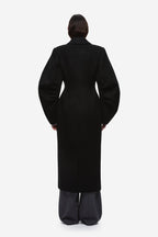 Back view of black wool long coat with center seam and notched collar.