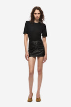 Black ruched leather mini skirt on model, fitted shape with front waist ruching