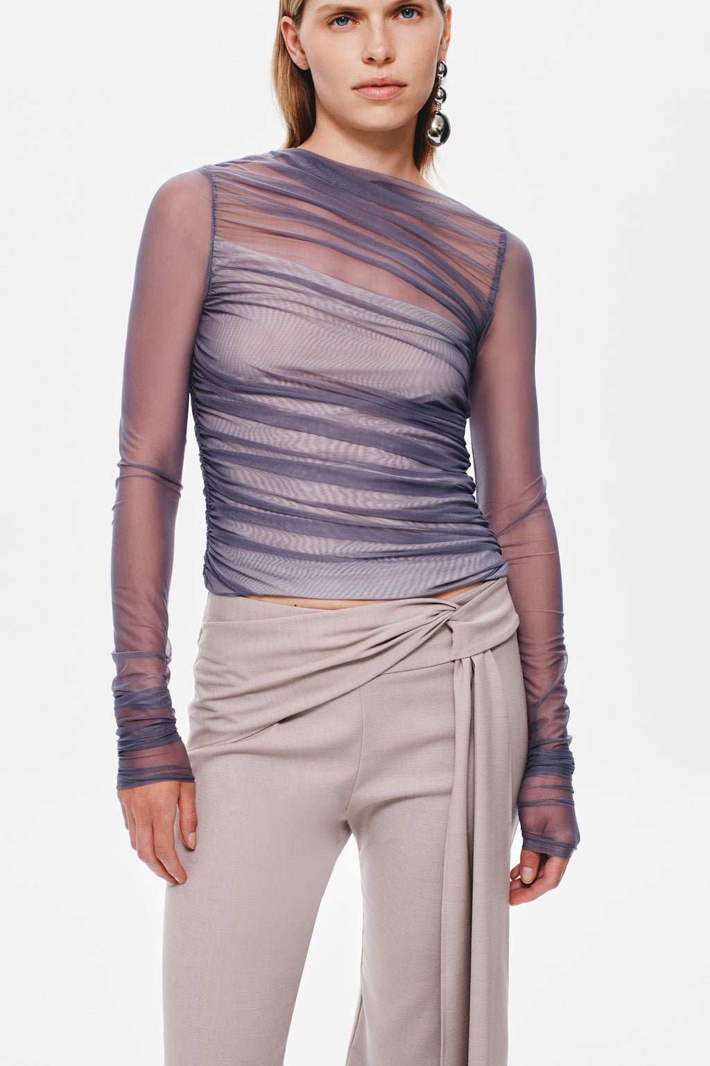 Stone suiting pants close-up: draped waist tie with knot at center front.
