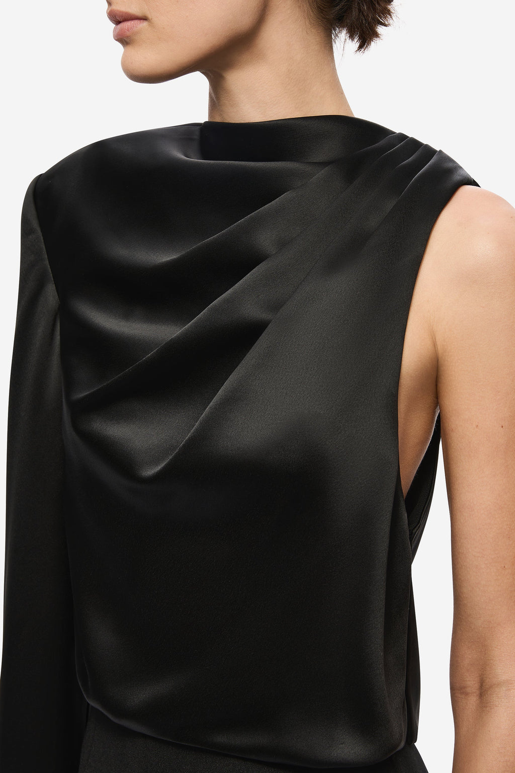 Black satin sleeveless top close-up with glossy cowl folds